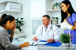 Concerned doctor discussing file with patient in office 4NXQl0