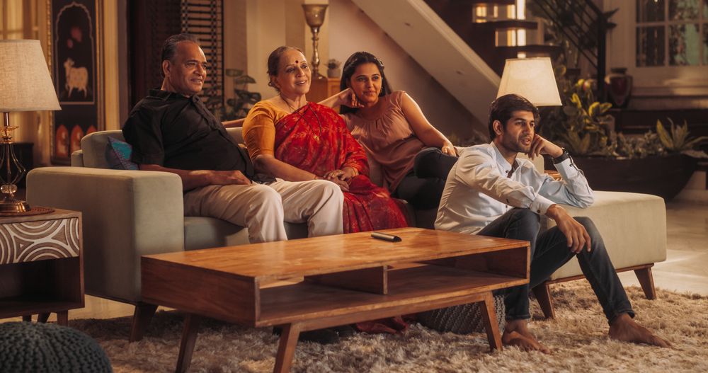 Portrait of Happy Indian Family Enjoying Movie Playing on TV at Home Together.