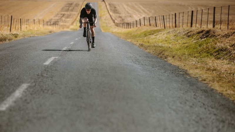 Pro bike rider cycling uphill on empty road