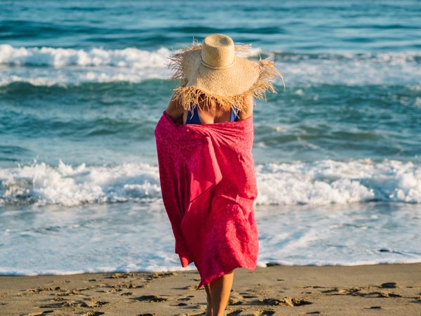 Woman with pink pareo on sandy beach