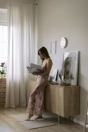 Woman standing with a large book in a bedroom