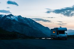 Camper car on road along snowy mountains