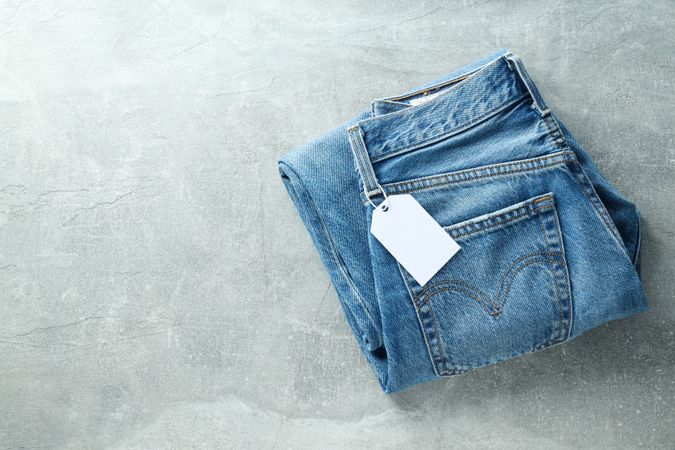 Folded jeans with a tag on a light background