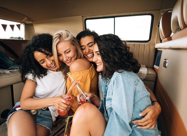 Female friends embracing in the back of a van