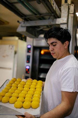 Latino baker with tray of dough balls
