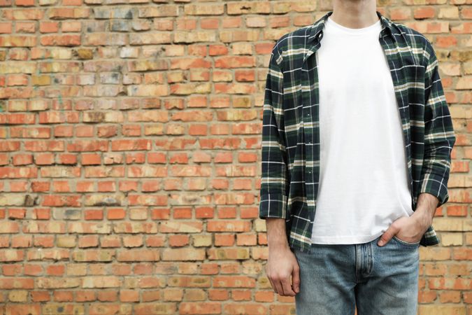 Men in t-shirt and checkered shirt against brick wall, copy space