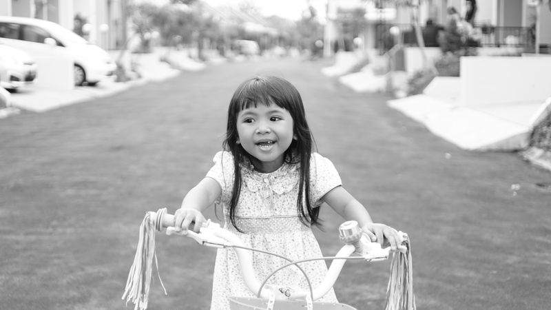 Monochrome photo of girl riding a bicycle on the street