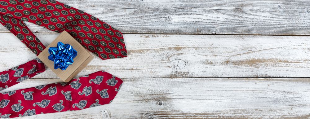 Happy Fathers Day giftbox with bow and two dress ties on rustic wood.
