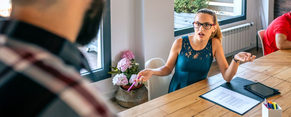 Surprised woman arguing with colleague for problems in coworking