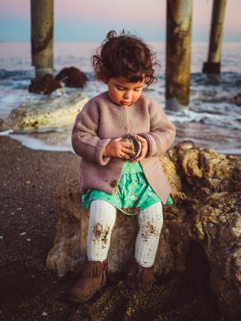small girl playing with seashell