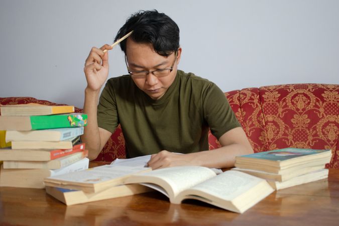 Asian young male reading book with frustrated gesture