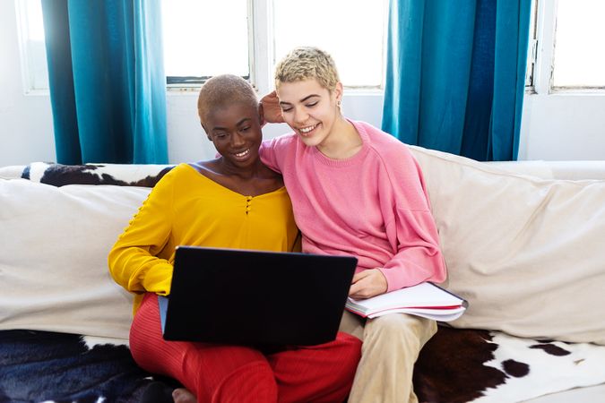 Best friends with a laptop resting on couch at home