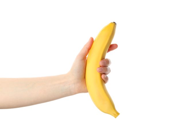 Female hand holds banana, isolated on light background