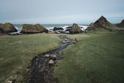 Woman walking along mountain river estuary