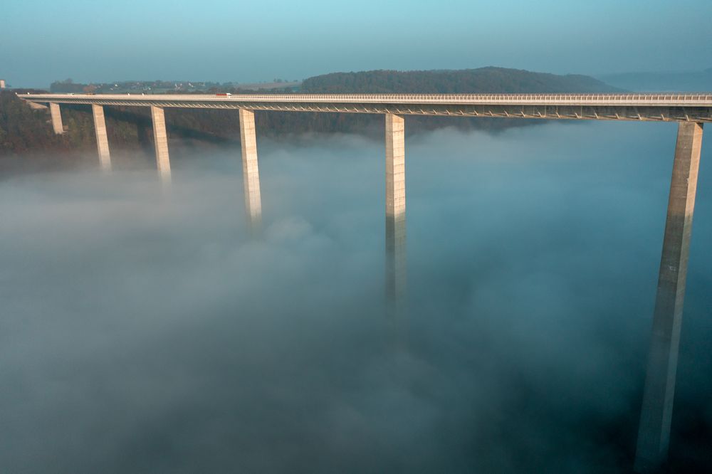 Autobahn bridge over dense fog, drone aerial view, at sunrise in Germany