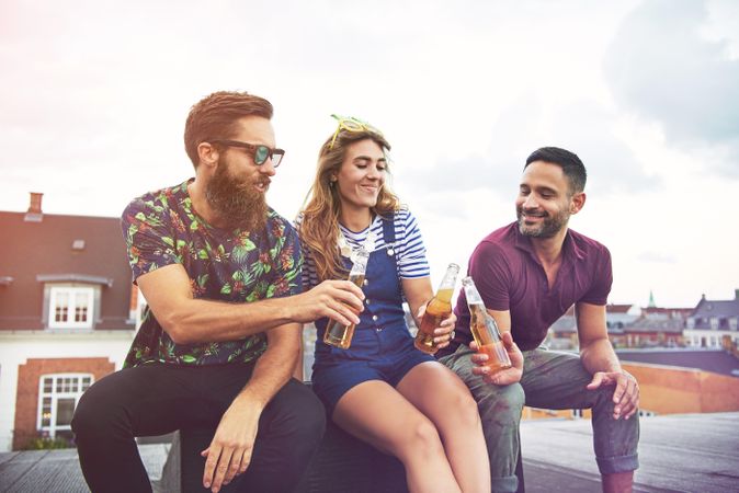 Relaxed friends toasting with bottles of beer outside