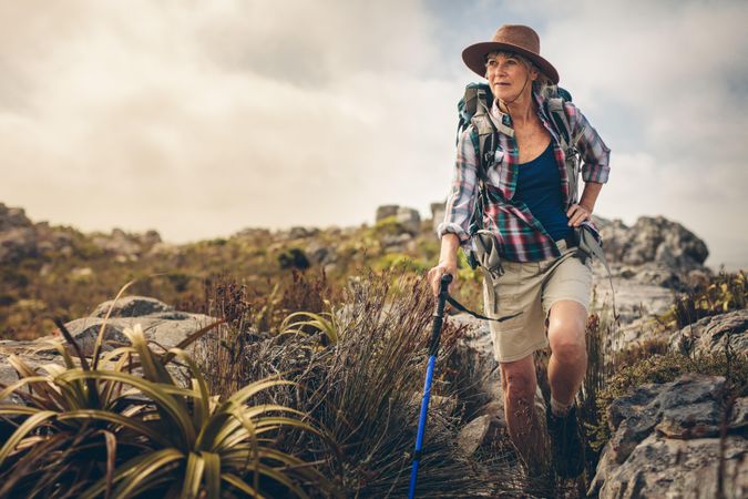 Mature woman walking through bushes and rocks during her hiking trip