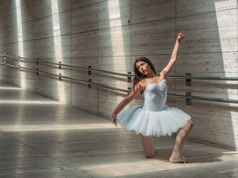 Ballerina doing ballet posing at rail in classroom