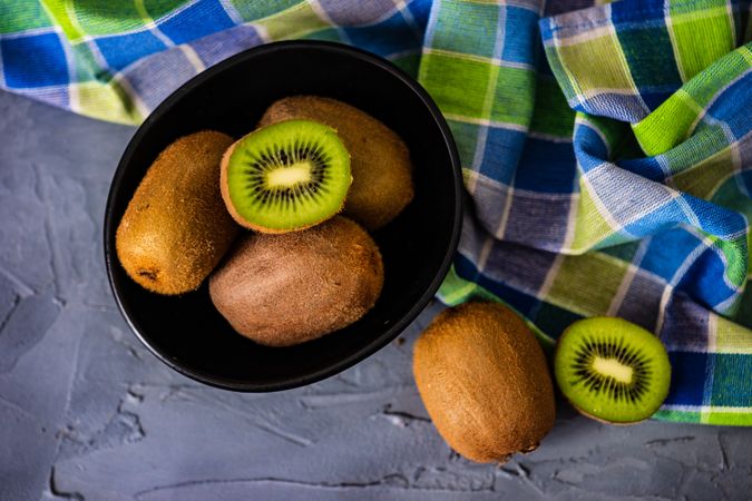 Bowl of kiwi fruits with one halved on top
