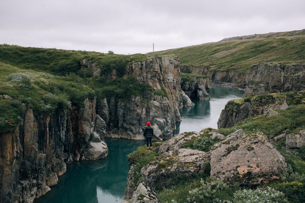 Woman standing on edge of cliffs over water