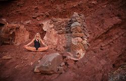 Woman sitting on top of rock and practicing yoga