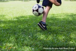 Cropped image of boy playing soccer ball on green grass field 49Yly4