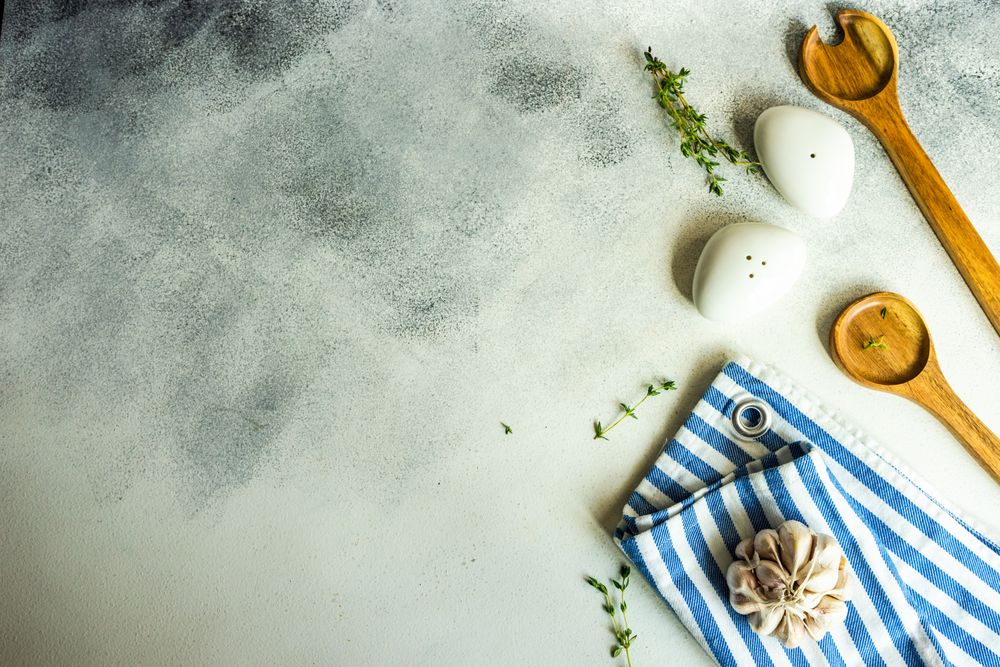 Top view of salt and pepper shakers, thyme and garlic on concrete background with copy space