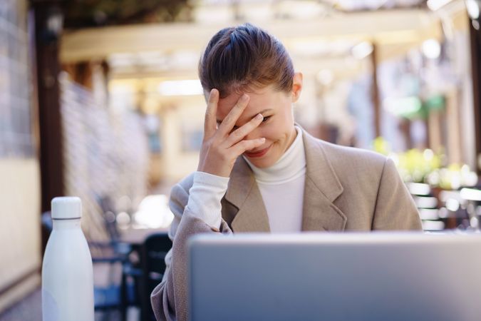 A frustrated professional is trying to work on a laptop outside, facing many distractions