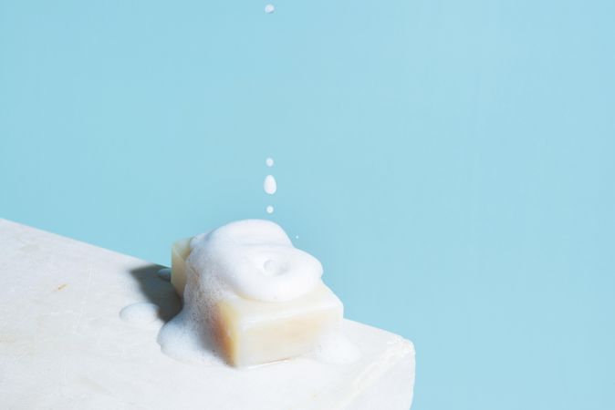 Piece of white soap and falling foam, minimal composition