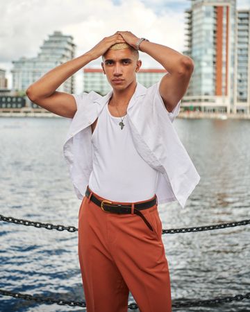 Stylish young man with both hands on head with river in background