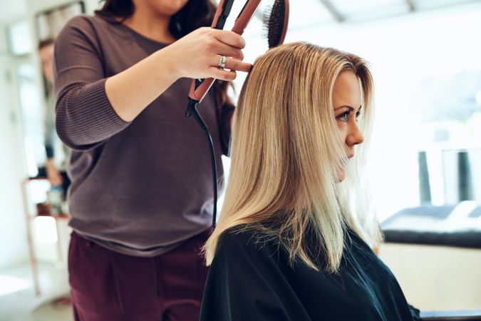 Close up of a woman sitting at a hair salon and getting her hair styled