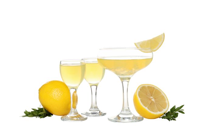 Lemons and cocktail glasses with limoncello, isolated on light background