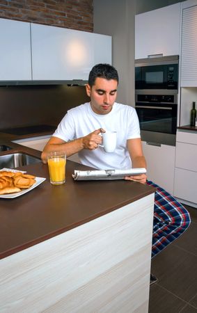 Man reading tablet during breakfast with cup of coffee and pastries