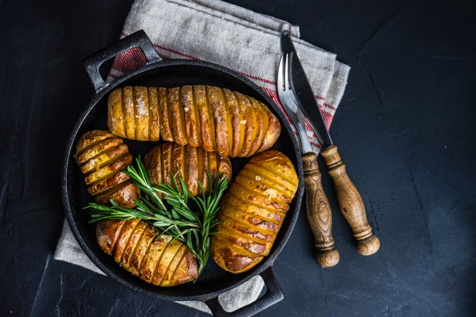 Potato fans in cast iron pan with rosemary with space for text