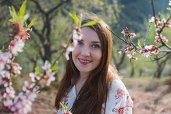 Young happy woman between trees in garden