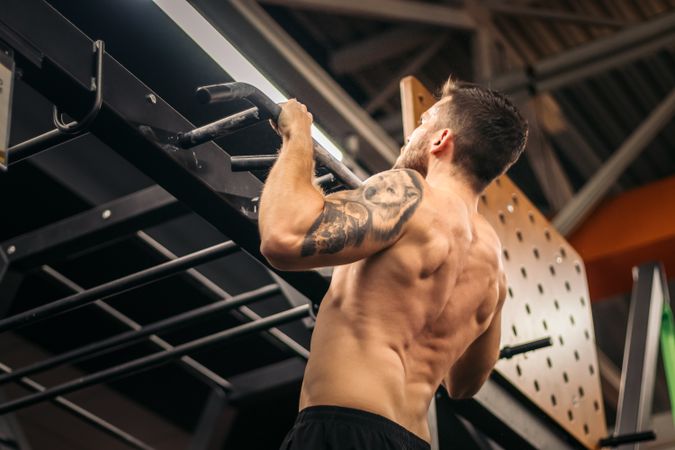 male athlete doing pull ups in a gym