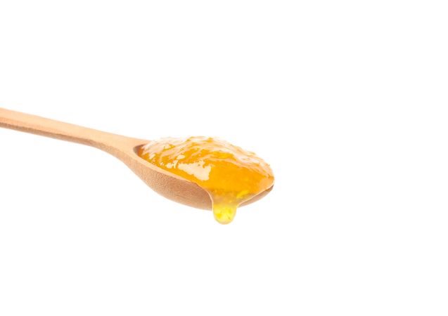 Spoon with apricot jam isolated on plain background