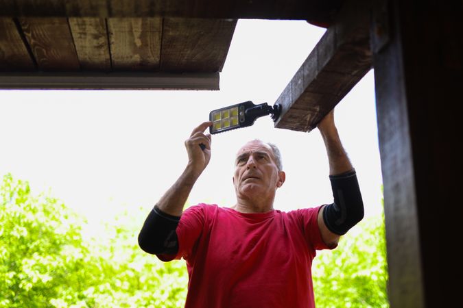 Older Man Using LED Work Light Under Wooden Roof