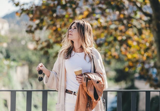 thoughtful woman leaning on handhold and looking along