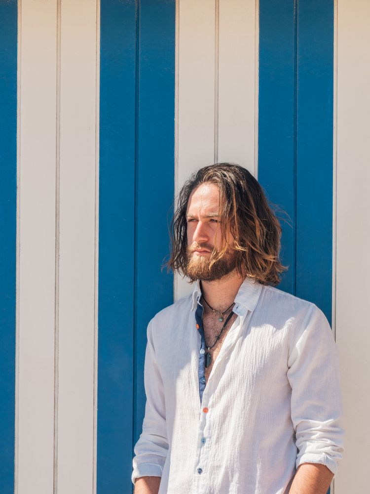 Cheerful guy standing near striped wall