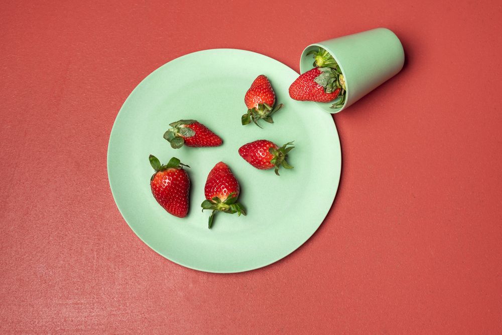 Harvested strawberry in green glass falling over