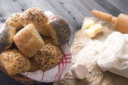 Basket with bread rolls and ingredients on rustic table