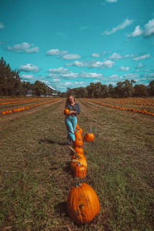 Girl in field holding pumpkin in pumpkin patch farm