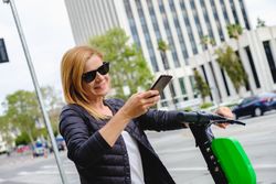 Woman browsing smartphone and riding electric scooter