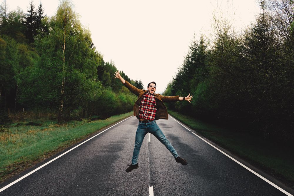 Man jumping on remote empty road