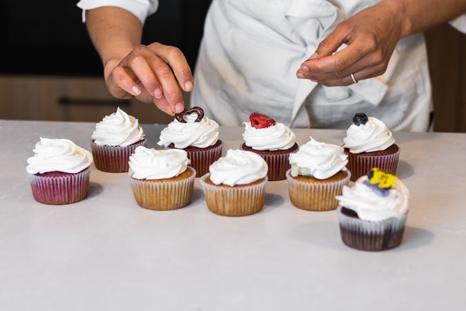 Anonymous baker decorating cupcakes at table