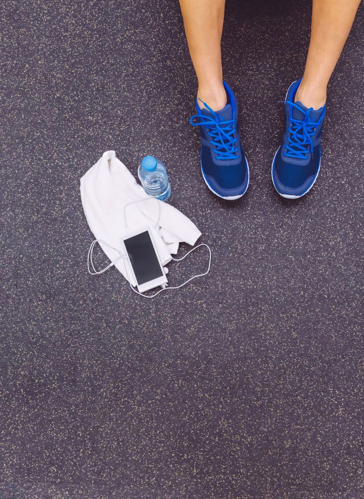 Top view of person sitting next to phone and water bottle in gym