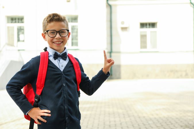 Boy with backpack against school building, space for text