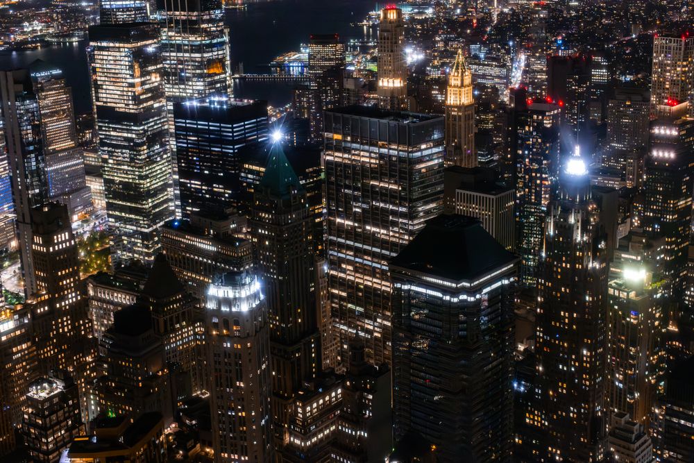 Aerial View of Manhattan Architecture at Night. Evening Shot of Financial Business District from a Helicopter. Scenery of Historic Office Towers, Illuminated Skyscrapers