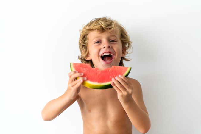 Cheerful boy eating fresh watermelon
